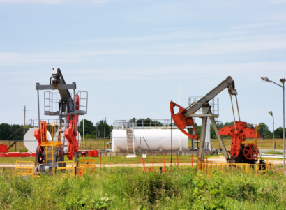 Oil pump in grassy field near street lights and white tank