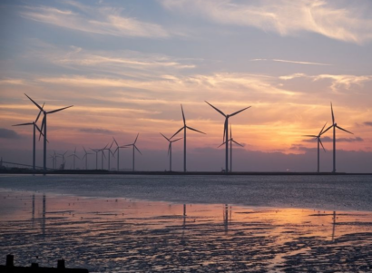 Windmills during a sunset near a small body of water.