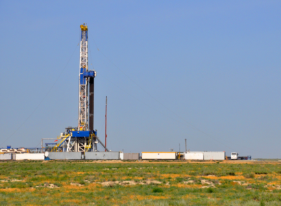 View of drilling rig installation during the day. There are shipment containers nearby.