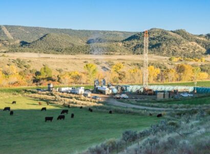 Drilling Fracking Rig in a mountain valley near a field full of cattle grazing.