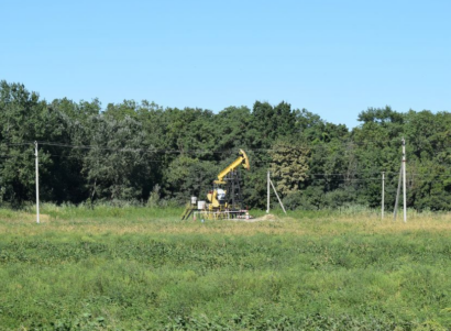 Oil well in a grassy field near trees