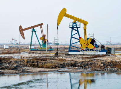 Two oil and gas wells in dirt near water